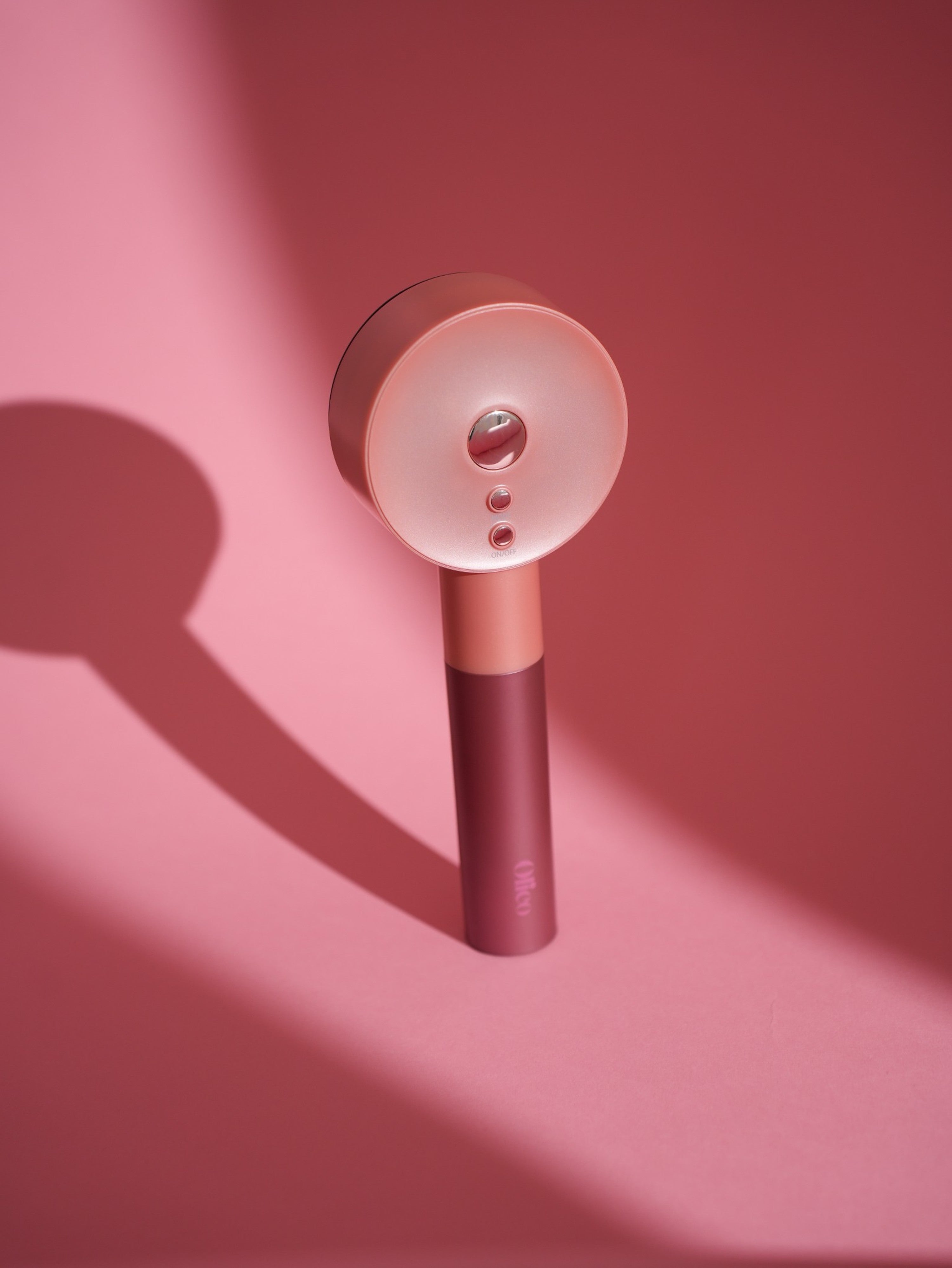 Rosé gouden OLIEO scalp massager tegen roze achtergrond